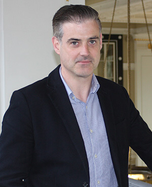 garrett wears a blue short and black blazer in this portrait