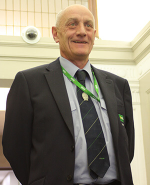 gpo security guard stands with arms behind back wearing a uit and striped tie
