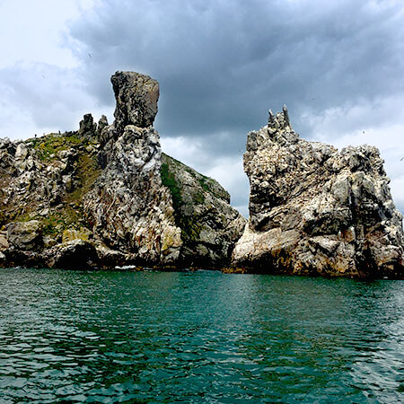 the cliffs at ireland's eye stand high above the green water